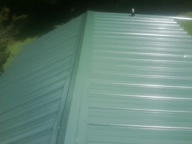 New green metal panels meeting at the ridge of a roof — Flat Roof Repair work by our crew in Rangely